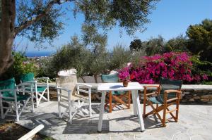 Eleonas Apartments في Sifnos: طاولة وكراسي على فناء به زهور