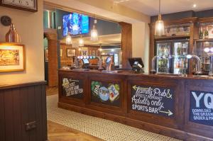 a bar in a restaurant with a counter at The Broughton Hotel by Greene King Inns in Milton Keynes
