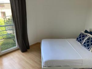 - un lit blanc dans une chambre avec fenêtre dans l'établissement True Hospitality, à Louvain-la-Neuve