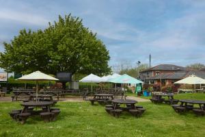 a group of picnic tables with umbrellas on the grass at The Broughton Hotel by Greene King Inns in Milton Keynes