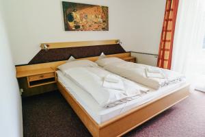 a bed with white sheets and pillows in a room at Gästehaus Frank in Velden am Wörthersee