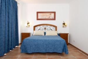 1 dormitorio con cama azul y cortinas azules en Apartment Limonade Deluxe Main Center Playa Blanca By PVL, en Playa Blanca