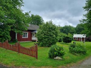 a red house with a fence in the yard at Slättö 17 Lammhult in Lammhult