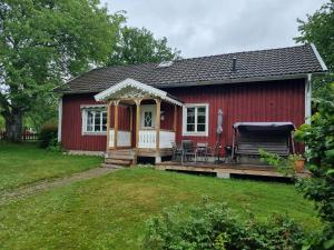 a red shed with a porch and a deck at Slättö 17 Lammhult in Lammhult