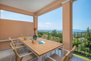 a balcony with a wooden table and chairs at Villa Oleander Apartman Aria in Poljane