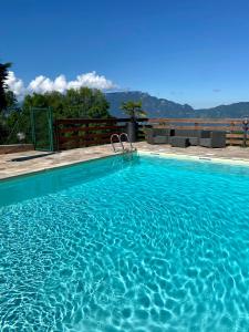 uma grande piscina azul com montanhas ao fundo em Logis Hôtel Le Bellevue em Trévignin
