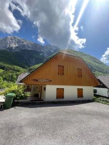 a large wooden barn with mountains in the background at VILA VALANGA in Bovec