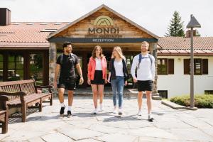 eine Gruppe von Menschen, die vor einem Gebäude spazieren in der Unterkunft MONDI Resort und Chalet Oberstaufen in Oberstaufen