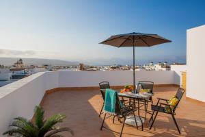 eine Terrasse mit einem Tisch, Stühlen und einem Sonnenschirm in der Unterkunft Edificio Manuel de Falla Apartamentos in Barbate