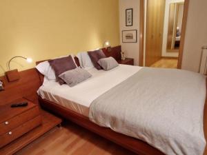 een slaapkamer met een groot bed en een houten nachtkastje bij Homing Sabadell 73 in Sabadell