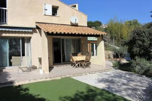 um pátio de uma casa com uma mesa e cadeiras em Petite villa dans copropriété avec piscine et vue mer. em Hyères