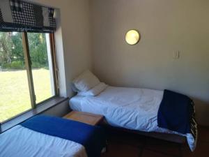 niewielka sypialnia z 2 łóżkami i oknem w obiekcie The 10th Hole - Golf Estate w mieście Villiersdorp