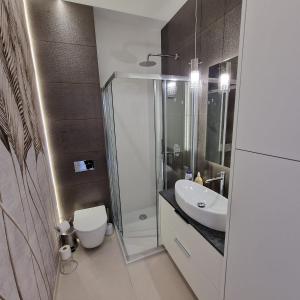 uma casa de banho com um chuveiro, um WC e um lavatório. em Apartamenty przy nowej plaży 1 em Sława