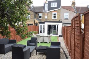 un patio trasero con sillas, una mesa y una valla en 7 Bedroom house with Garden, en Londres