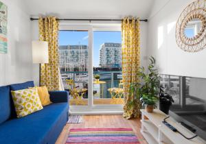 ein Wohnzimmer mit einem blauen Sofa und einem großen Fenster in der Unterkunft On the Water 4 with Free Parking By My Getaways in Brighton & Hove