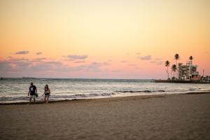 2 personnes marchant sur la plage au coucher du soleil dans l'établissement 2BR Condo at Isla Verde Beach, à San Juan