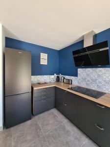 a kitchen with black cabinets and blue walls at Gîte la Couzinette 3km du parc Puy du Fou in Les Épesses