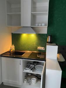 una cocina con armarios blancos y una pared verde en Fontush Boutique Hotel, en Ivano-Frankivsk