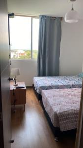 a room with two beds and a table and a window at HABITACION DOBLE con baño compartido en apartamento compartido in Bucaramanga