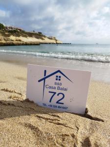 un cartel en la arena en una playa en b&b Casa Balai 72 a 150 mt dal mare, en Porto Torres