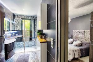 a bathroom with a sink and a bed in a room at O jardin des Sens -Séjour Bien-être & détente &Jacuzzi in Béziers