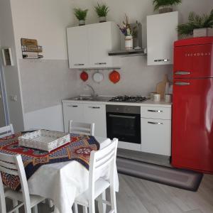 uma cozinha com uma mesa e um frigorífico vermelho em Casa Aurora em Terrasini
