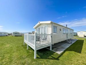 a white house with a porch on a grass field at Lovely Caravan With Decking At Sand Le Mere Park In Yorkshire Ref 71032tv in Tunstall