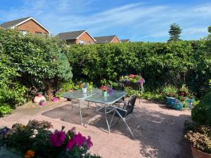 una mesa y sillas en un jardín con flores en Spacious 5 double bed bedroom bungalow near Belfast en Lisburn