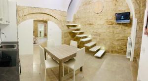 ein Esszimmer mit einem Holztisch und einer Steinmauer in der Unterkunft Le Mura di Gabry in Bari