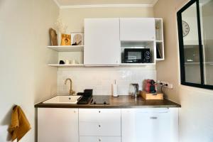 a kitchen with white cabinets and a sink and a microwave at L'Iconique in Concarneau +12 photos