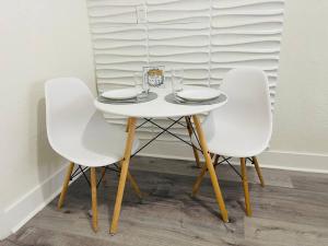 een witte tafel met twee witte stoelen en glazen erop bij Alma Guest Suite in Miami