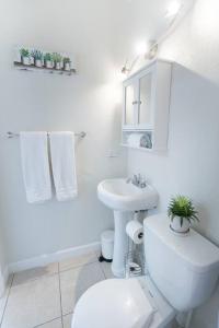 a white bathroom with a toilet and a sink at Alma Guest Suite in Miami