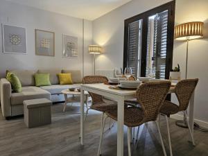 comedor y sala de estar con mesa y sillas en IMEDA Apartamentos Piedra Santa, en Granada