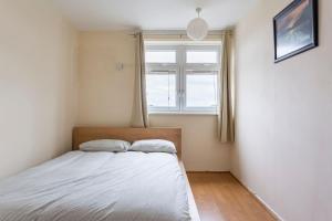 Schlafzimmer mit einem Bett und einem Fenster in der Unterkunft Home From Home in London