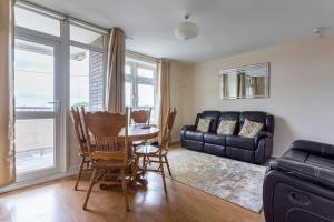 ein Wohnzimmer mit einem Tisch, Stühlen und einem Sofa in der Unterkunft Home From Home in London