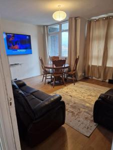 ein Wohnzimmer mit einem Sofa und einem Esstisch in der Unterkunft Home From Home in London