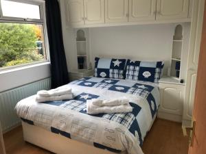a bedroom with a blue and white bed with towels on it at Spacious 5 double bed bedroom bungalow near Belfast in Lisburn