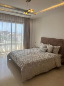 a bedroom with a large bed and a large window at Residence prestige in Nabeul