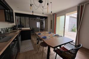 a kitchen with a wooden table with chairs and a sink at Elma Stay Location LEscale in Saint-Just