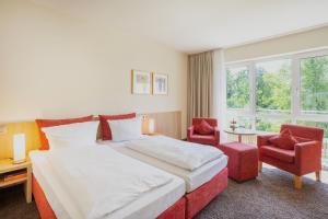 a hotel room with a large bed and two chairs at Concorde Hotel Viktoria in Kronberg im Taunus