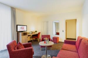 a living room with red chairs and a table at Concorde Hotel Viktoria in Kronberg im Taunus