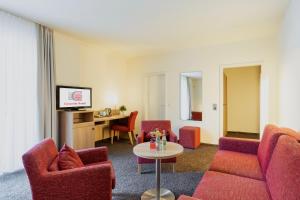 Concorde Hotel Viktoria في كرونبرج إم تانوس: غرفة معيشة مع كراسي حمراء وطاولة