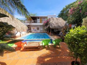 ein Schwimmbecken mit vier Stühlen und ein Haus in der Unterkunft Divanga Hostel and Diving in Taganga