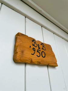 um sinal de madeira pendurado numa parede branca em Novecento Room and Breakfast Puglia em Massafra