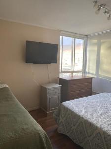 a bedroom with a bed and a flat screen tv at Amplio Departamento - Edificio Tranquilo in Antofagasta