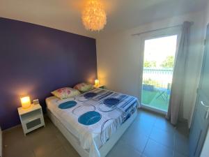 a bedroom with a bed and a window and a chandelier at Maison avec piscine, climatisée, proche plage in Roquebrune-sur-Argens