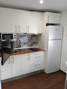 Apartamento Madreselva 36 في غرناطة: مطبخ فيه دواليب بيضاء وثلاجة بيضاء