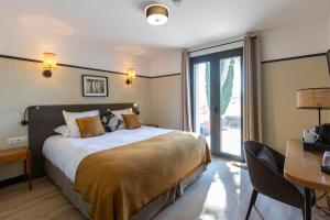 a bedroom with a bed and a desk and a window at Les Villas du Château de Lastours in Portel-des-Corbières