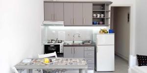 a small kitchen with a white refrigerator and a table at Andros Lighthouse Apartments in Mesariá