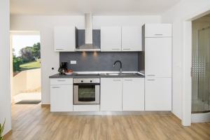 a kitchen with white cabinets and a sink at Apartments & Rooms Darrer in Poreč